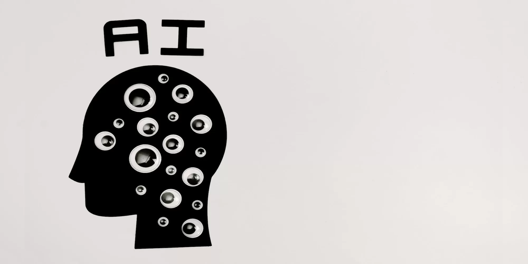 googly eyes on a silhouette of a face with the letters AI about Photo by Tara Winstead: https://www.pexels.com/photo/an-artificial-intelligence-illustration-on-the-wall-8849295/