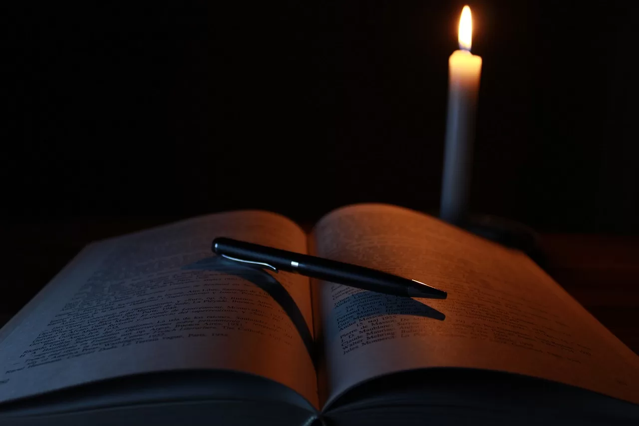 Open book with canddle in background