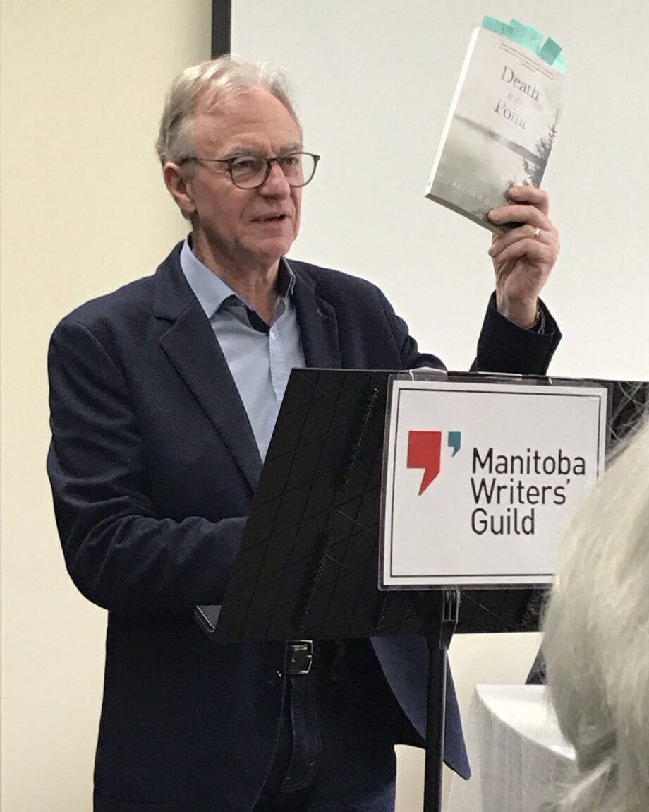 andrew dutfield holding up his book "Death at the Point" while standing at podium during book launch